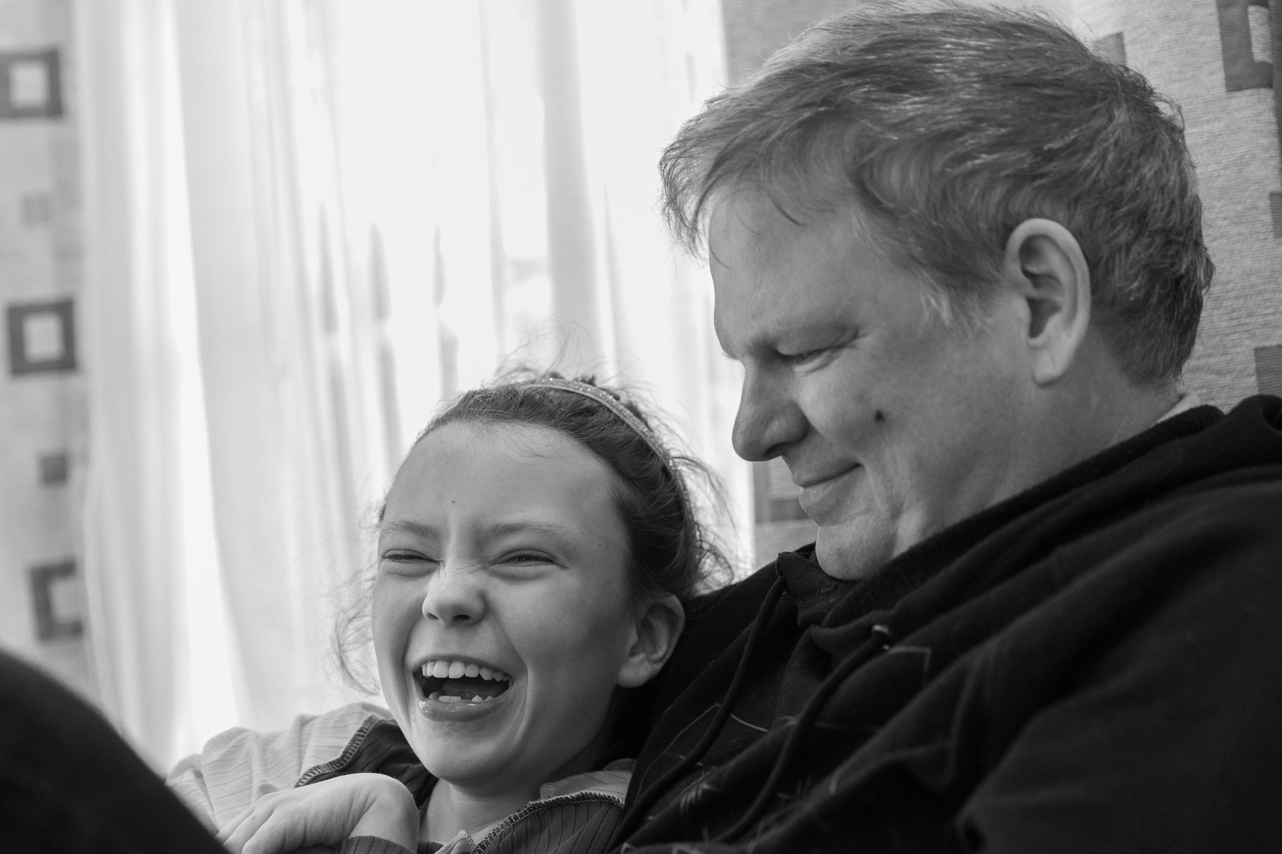 A young girl laughs as her father looks at her smiling. 