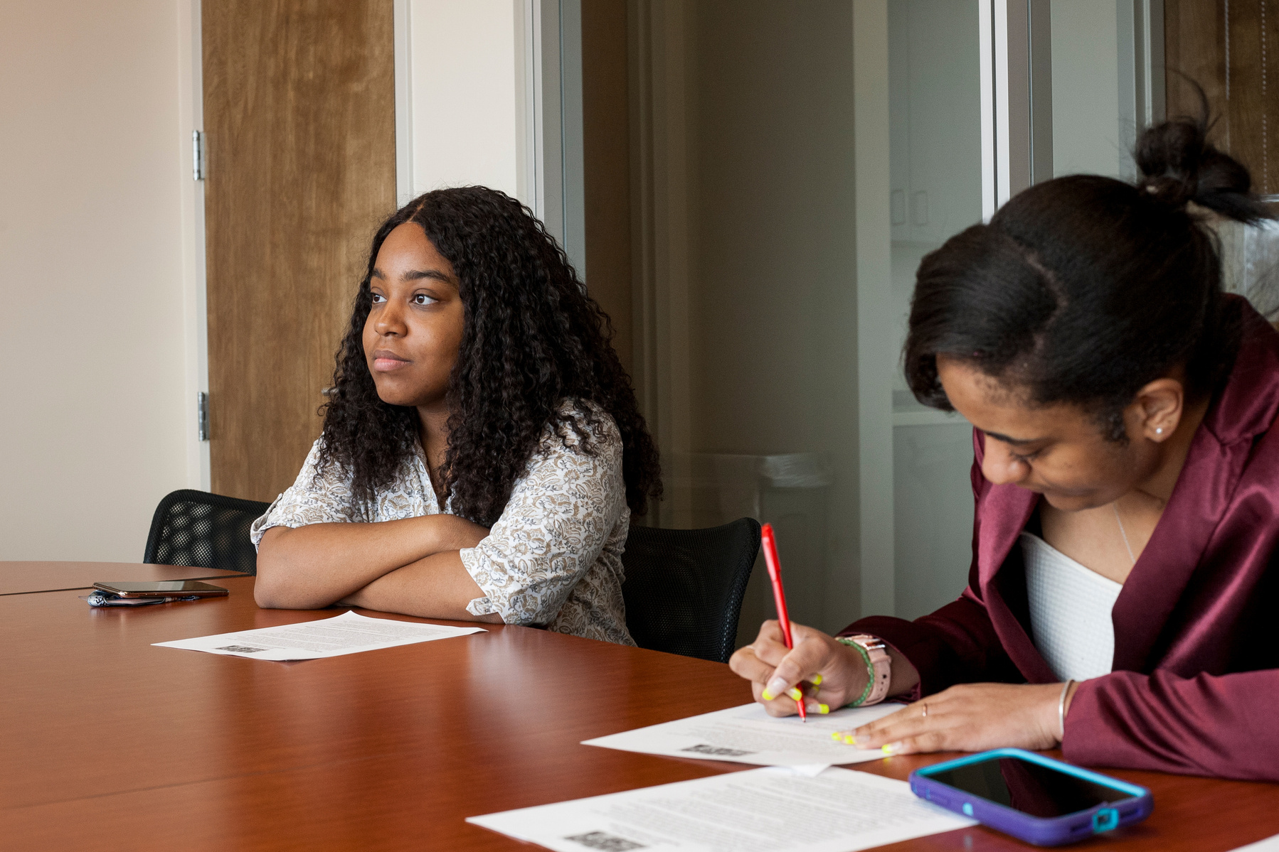 Two African American female college students sit at a conference table and work. 