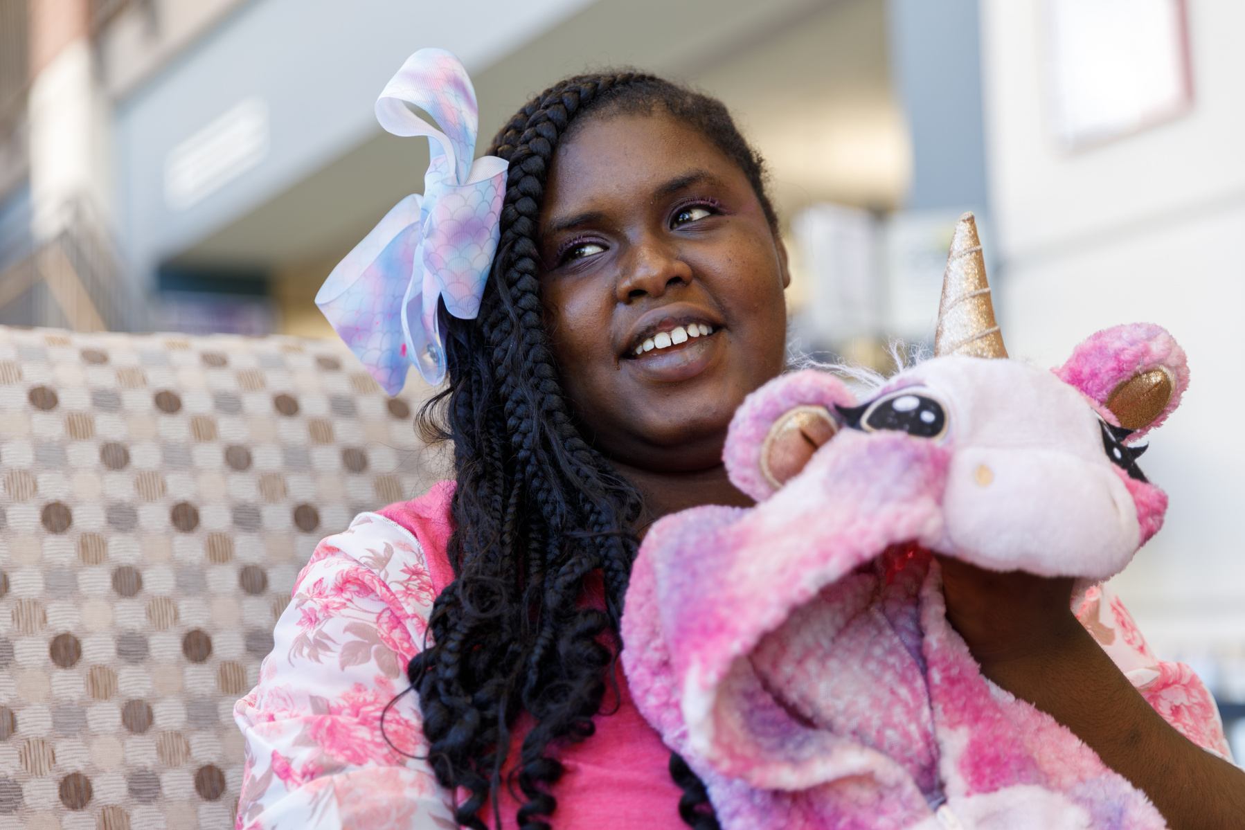 Young African American woman sits on a sofa with a stuffed unicorn