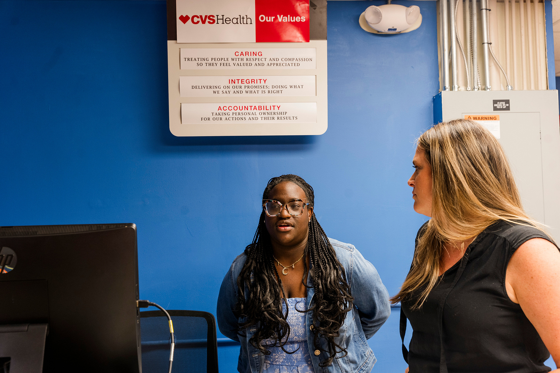 Young African American woman wears braids and talks to one of her instructors. 