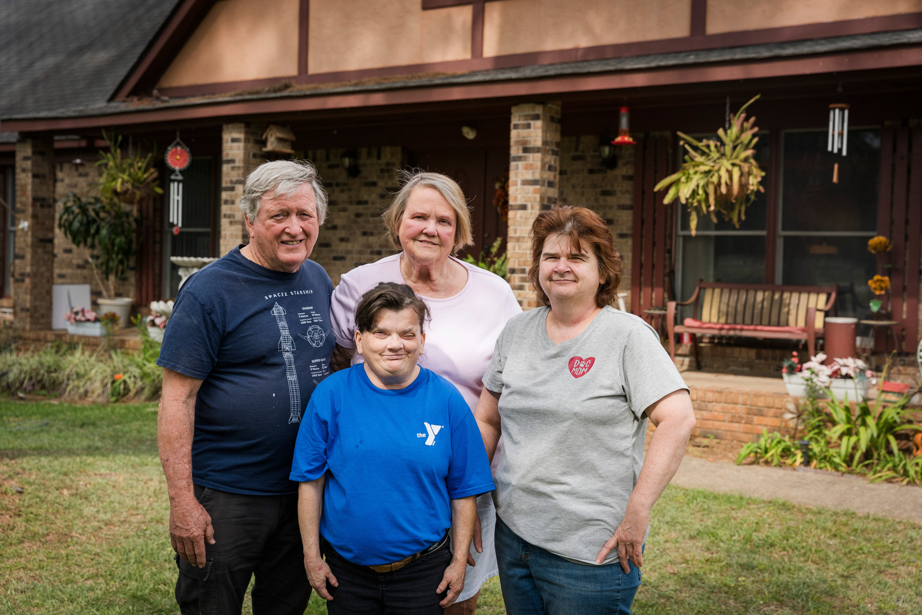 A family stands in front of a home and smiles for the camera.
