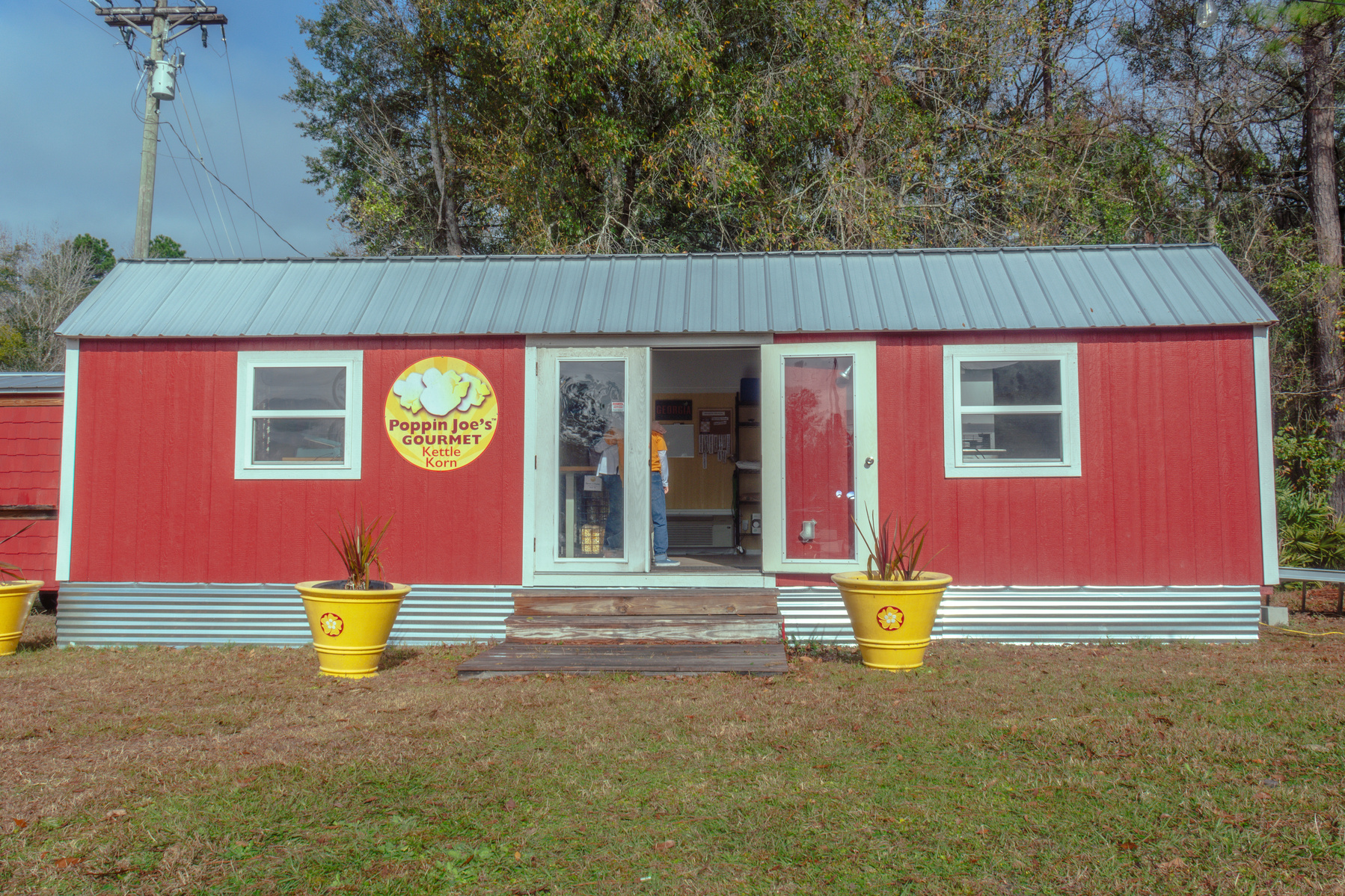 A red one story building sits with a green lawn in front of it.