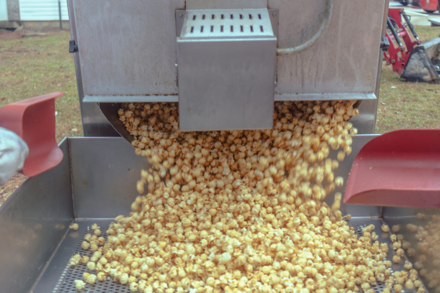 Popcorn pours out of a metal machine.