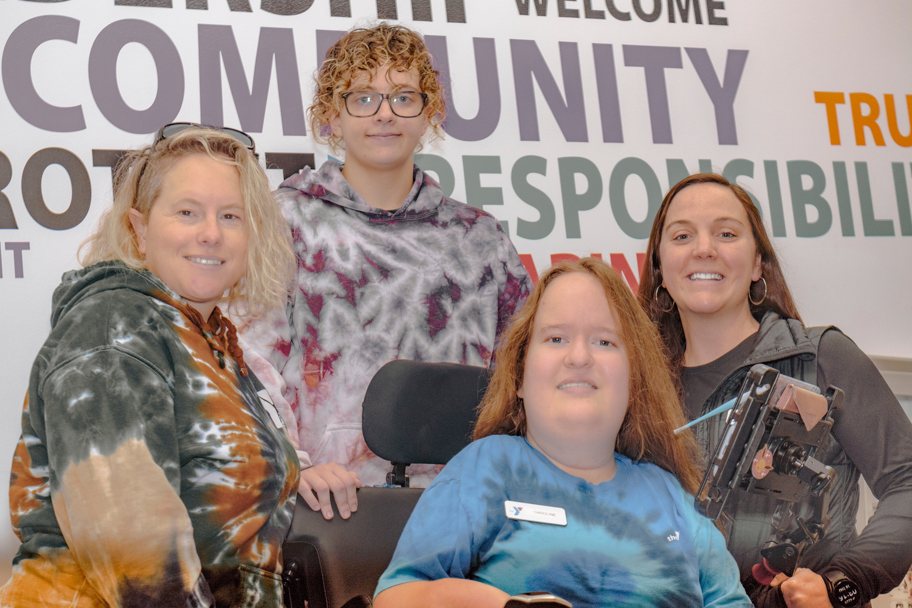 A group of four women pose in front of a sign that reads community responsibility.