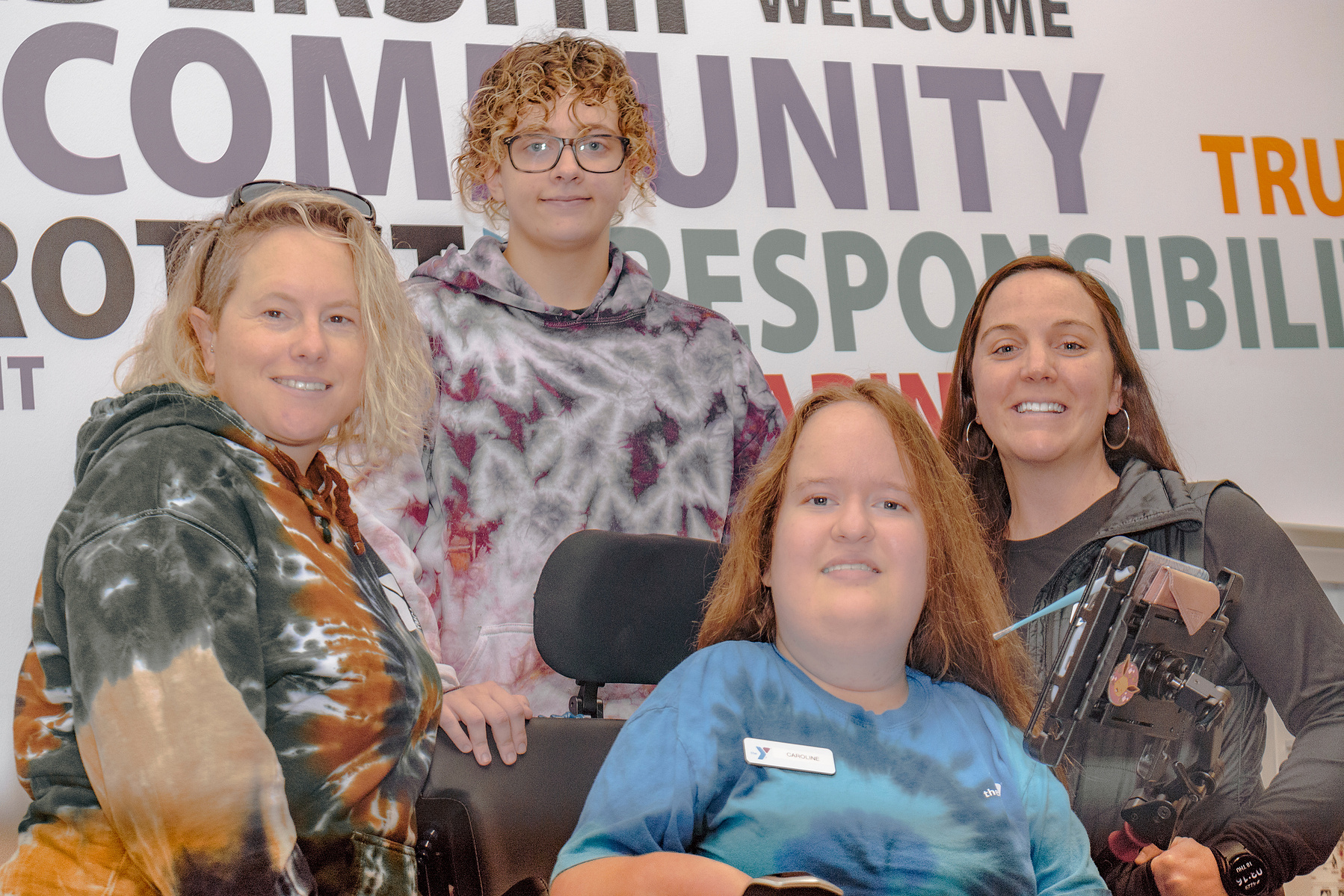 A group of four women pose in front of a sign that reads community responsibility.