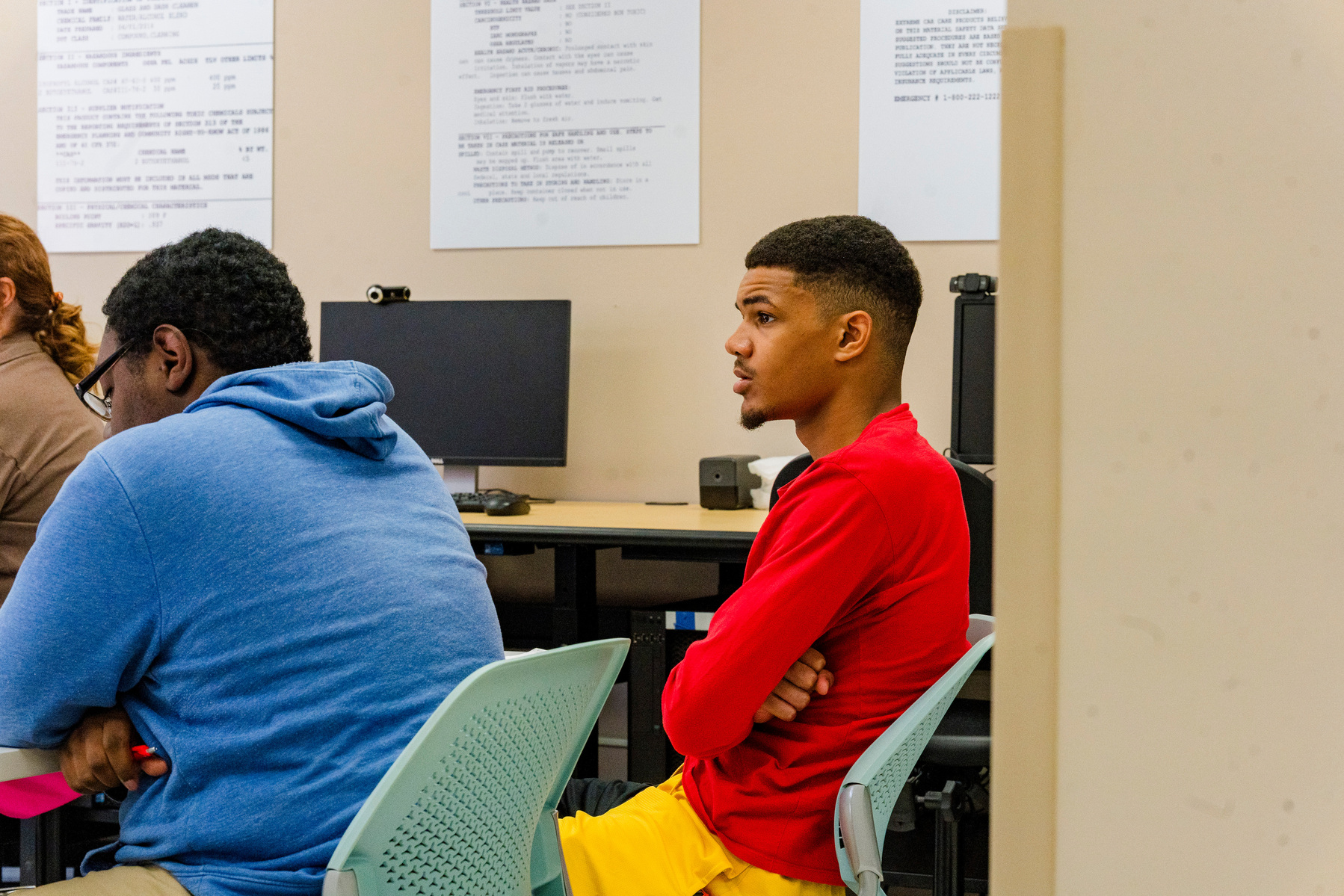 Two African American men sit in chairs in a classroom. 
