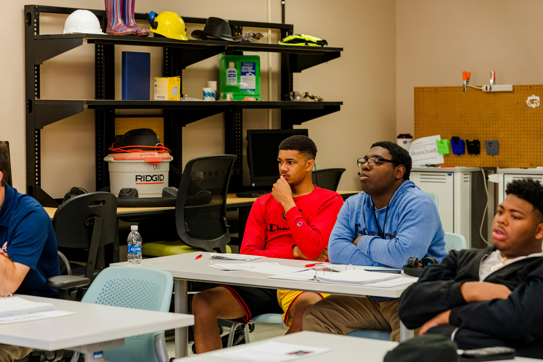 Young African American men sit at their desks in a classroom. 