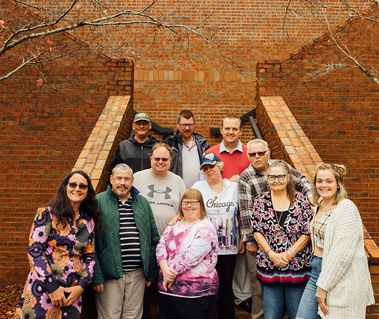 The Dream Weavers group stands on brick stairs outside. 