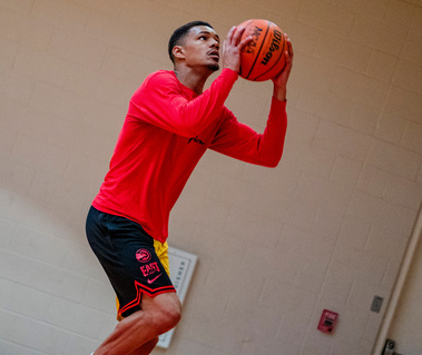 A young African American man shoots a basketball.