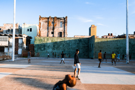 Kids playing football near the Parque Jose Marti in Havana. Colourful buildings act as a backdrop against the late afternoon sky.