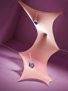 Die Zeit verläuft nicht mehr geradlinig, Zeit und Raum werden gekrümmt. Alles gerät ein bisschen in die schiefe Bahn. Lollies springen auf einem Trampolin. Die Person macht sich aus der Demenz einen Spaß.