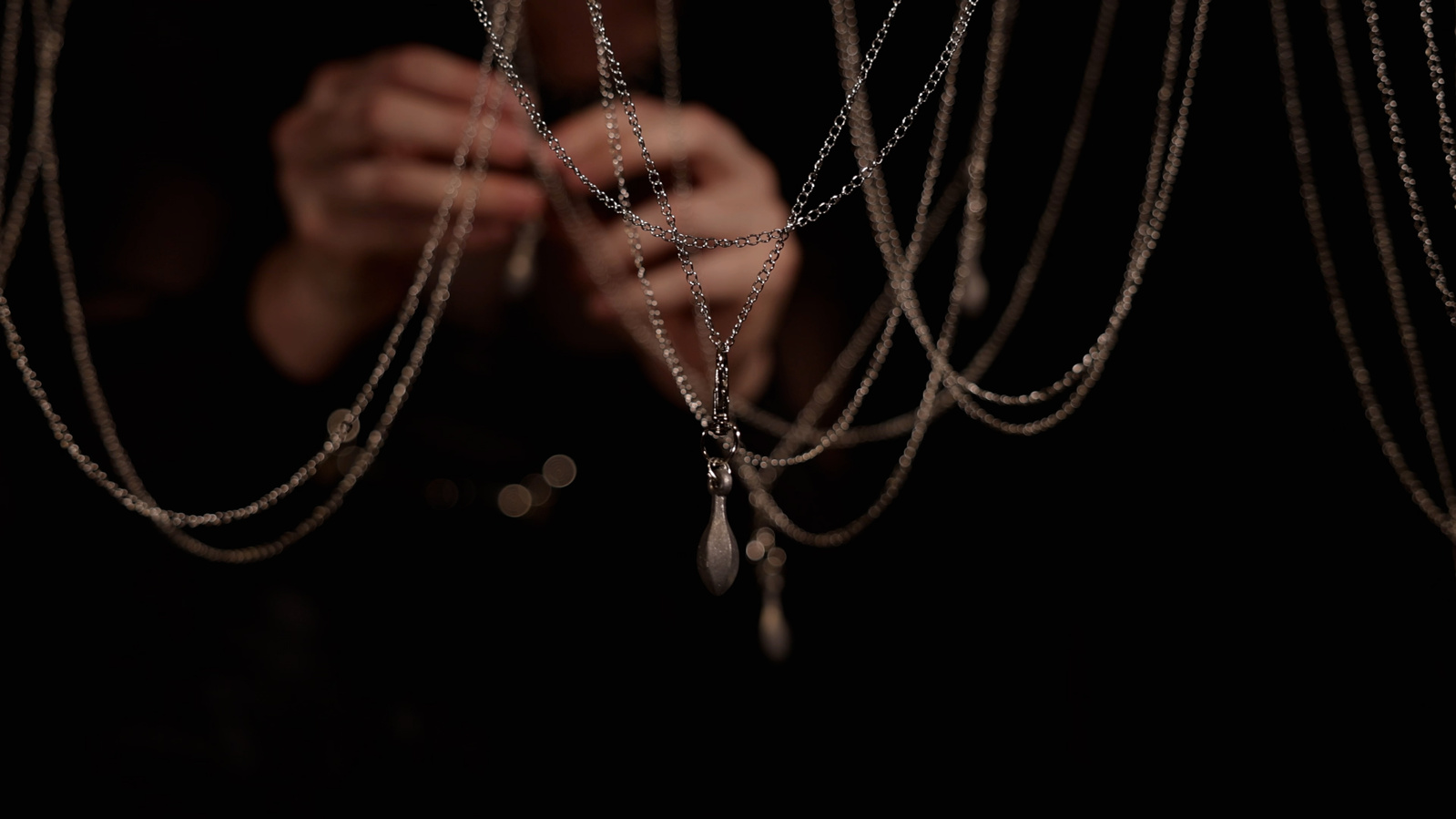 hands attaching weights to delicate hanging chain