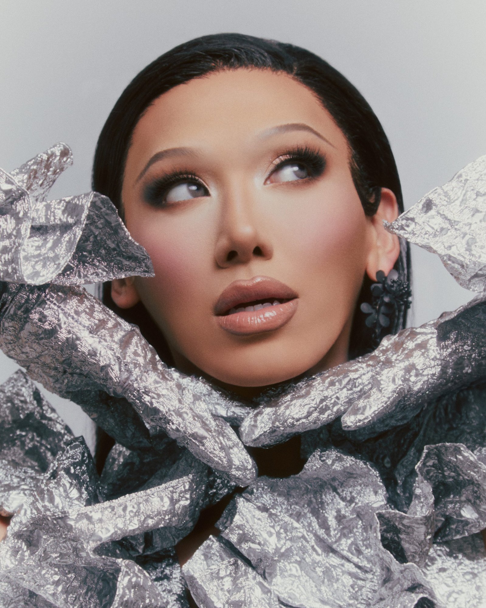 TikTok sensation and fan-favorite contestant of RuPaul's Drag Race, Vietnamese-American drag queen Plastique Tiara stuns in a silver dress with matching gloves and black earrings.