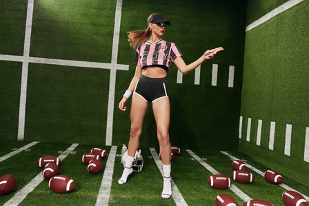 Spring 2024 sports apparel campaign for SHEIN, photographed in Hawthorne, Los Angeles. Model Daria Miko at Two Management wears a pink and black cutoff referee shirt, black visor, and sunglasses all by SHEIN. Football set design by Natasha Suely.