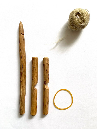 A handmade spindle made from tree branches and an elastic band.