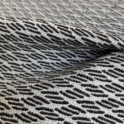 handwoven woolen fabric with a playfull pattern of black diagonal stripes on a light blue font by Joost Post