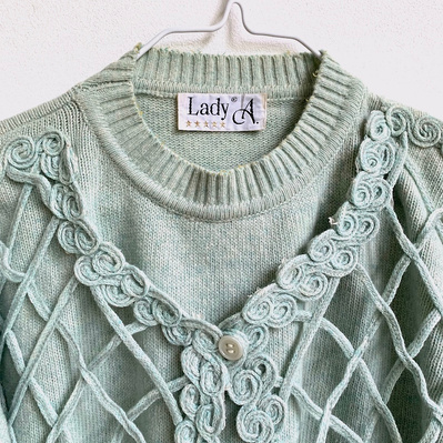 An elaborately decorated industrial knitted sweater ready to be unraveled.