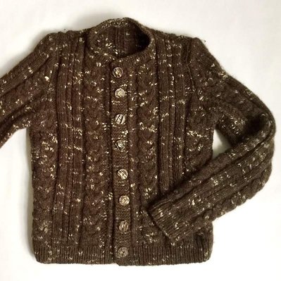 A brown hand-spun and hand-knitted cardigan before becoming a woven textile.