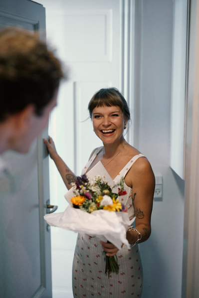 Kvinde åbner dør og smiler fordi hun har modtaget blomster fra et bud