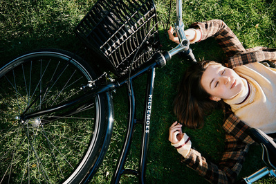 Kvinde ligger med lukkede øjne i grønt græs med Kildemoes cykler ved siden af