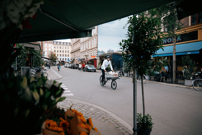 Mand cykler på lang cykel gennem gade med mennesker og butikker omkring sig
