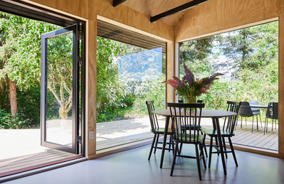 Spisebord i sommerhus med grøn udsigt gennem store vinduer