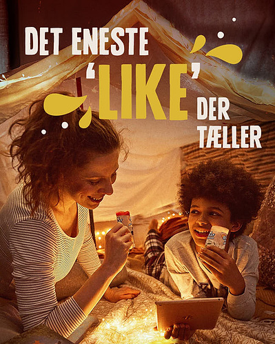 Dame og dreng ligger i en hyggelig hule og spiser sun lolly mens de kigger i en bog