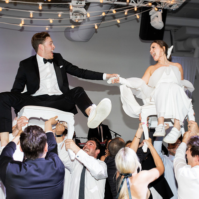 A couple being lifted on chairs during the hora at their wedding reception 