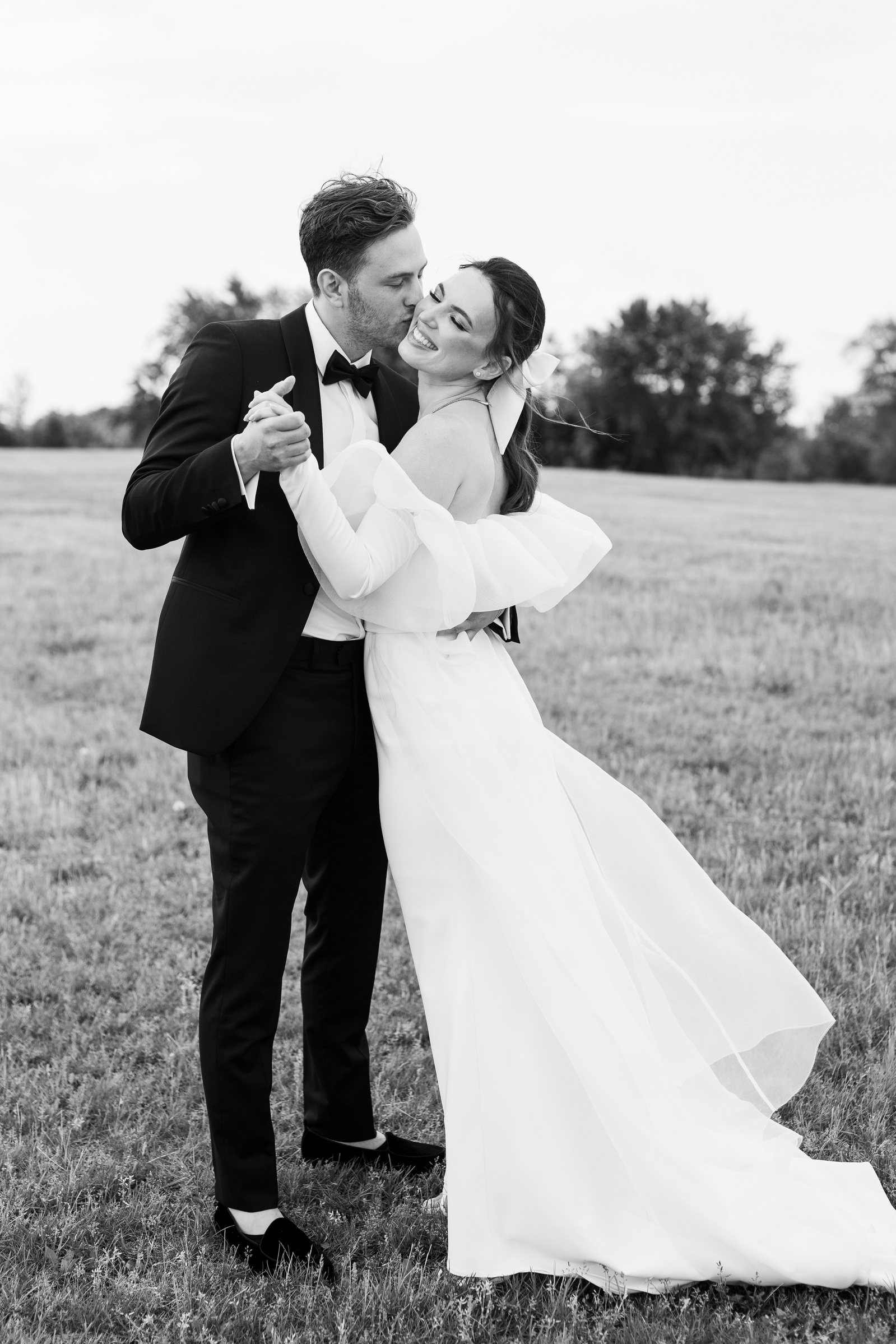 a couple dancing in a field on their wedding day