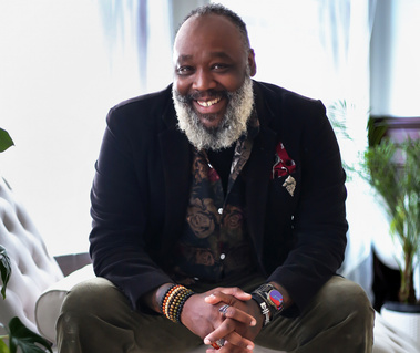A Dapper Mature African American Man with a grey beard sitting on a chais lounge chair