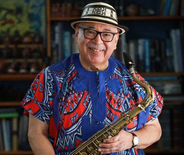 A musican holding a saxophone with a colorful Colombian style shirt and hat