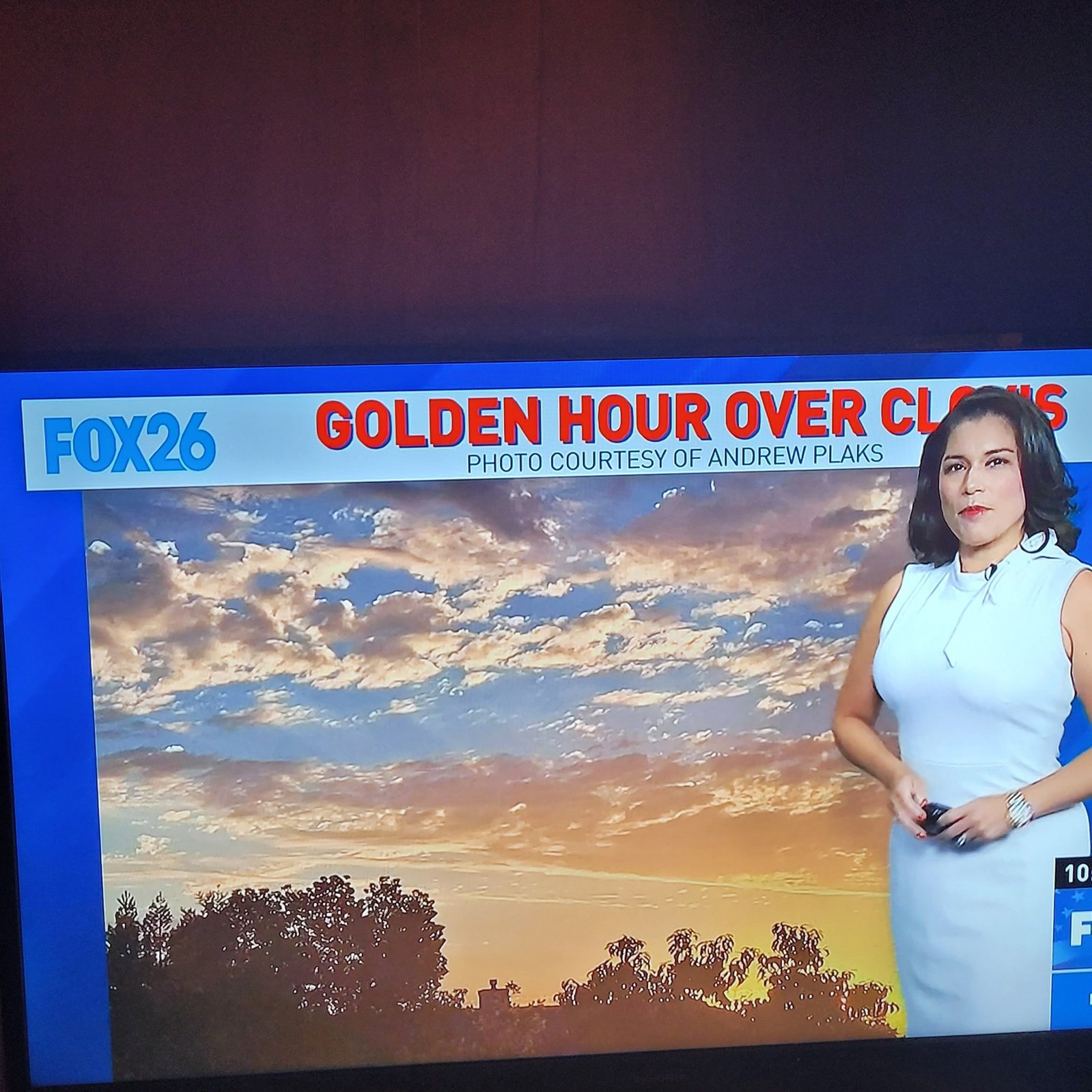 Newscaster gesturing over photo of sunrise. Text above reads: Golden Hour Over Clovis Photo Courtesy of Andrew Plaks