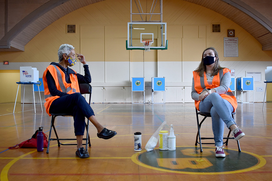 Volunteers Doriann Rosa-Boatwright and Emily sit at the sanitation area in the polling station at Veterans Memorial Recreation Center in San Bruno Park in San Bruno, CA on Sunday November 1, 2020. (Karina Patel)