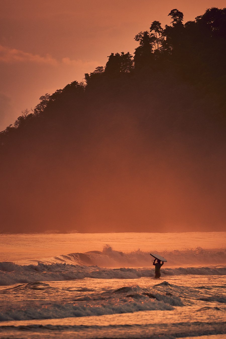 A surfer in playa hermosa in Costa Rica at sunset