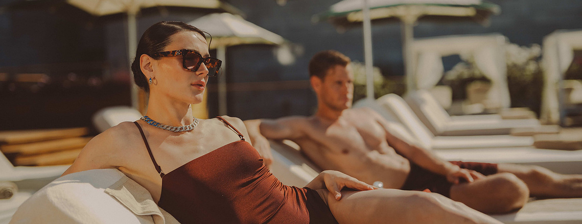 a couple are lying next to a pool in a high end hotel