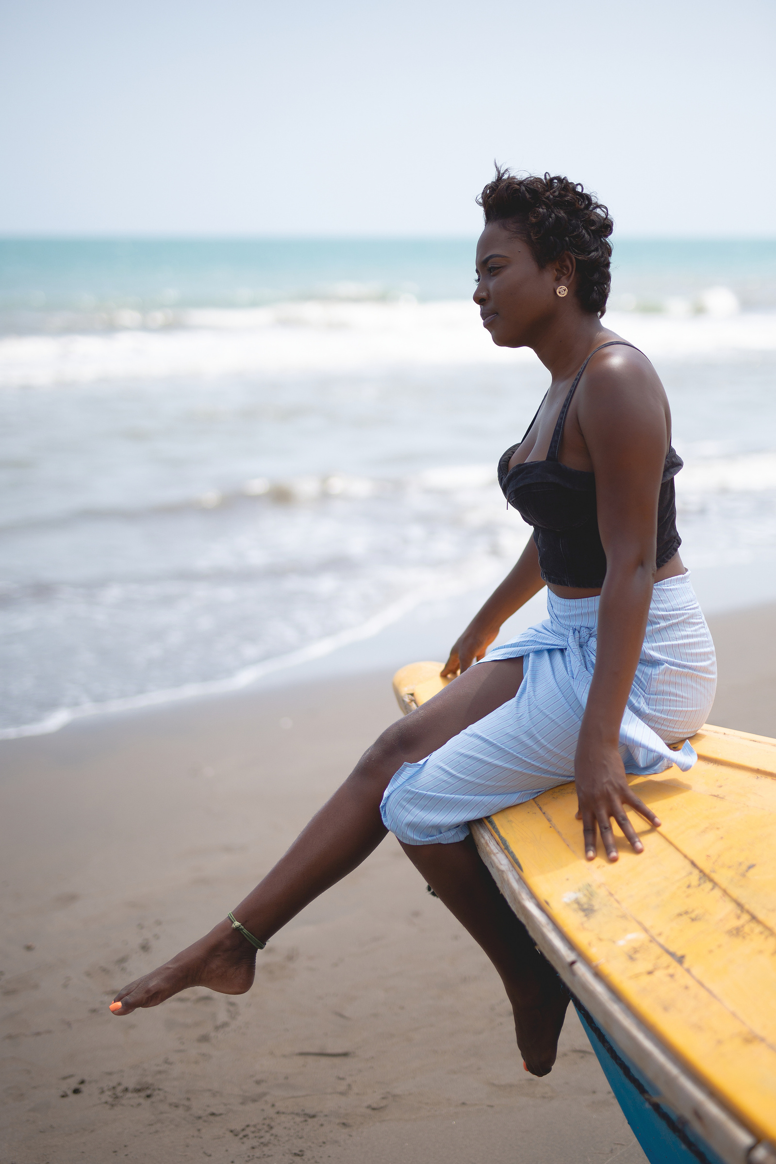 black jamiacan woman sitting on a canoe on a beach