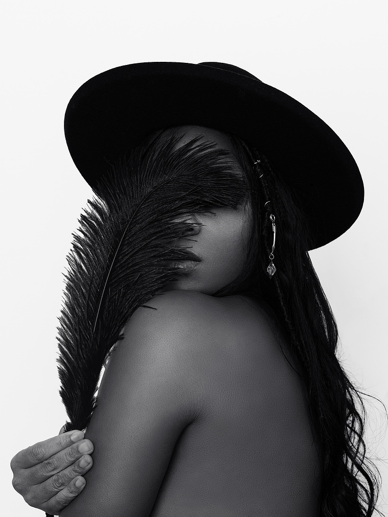 black woman with feather covering her face