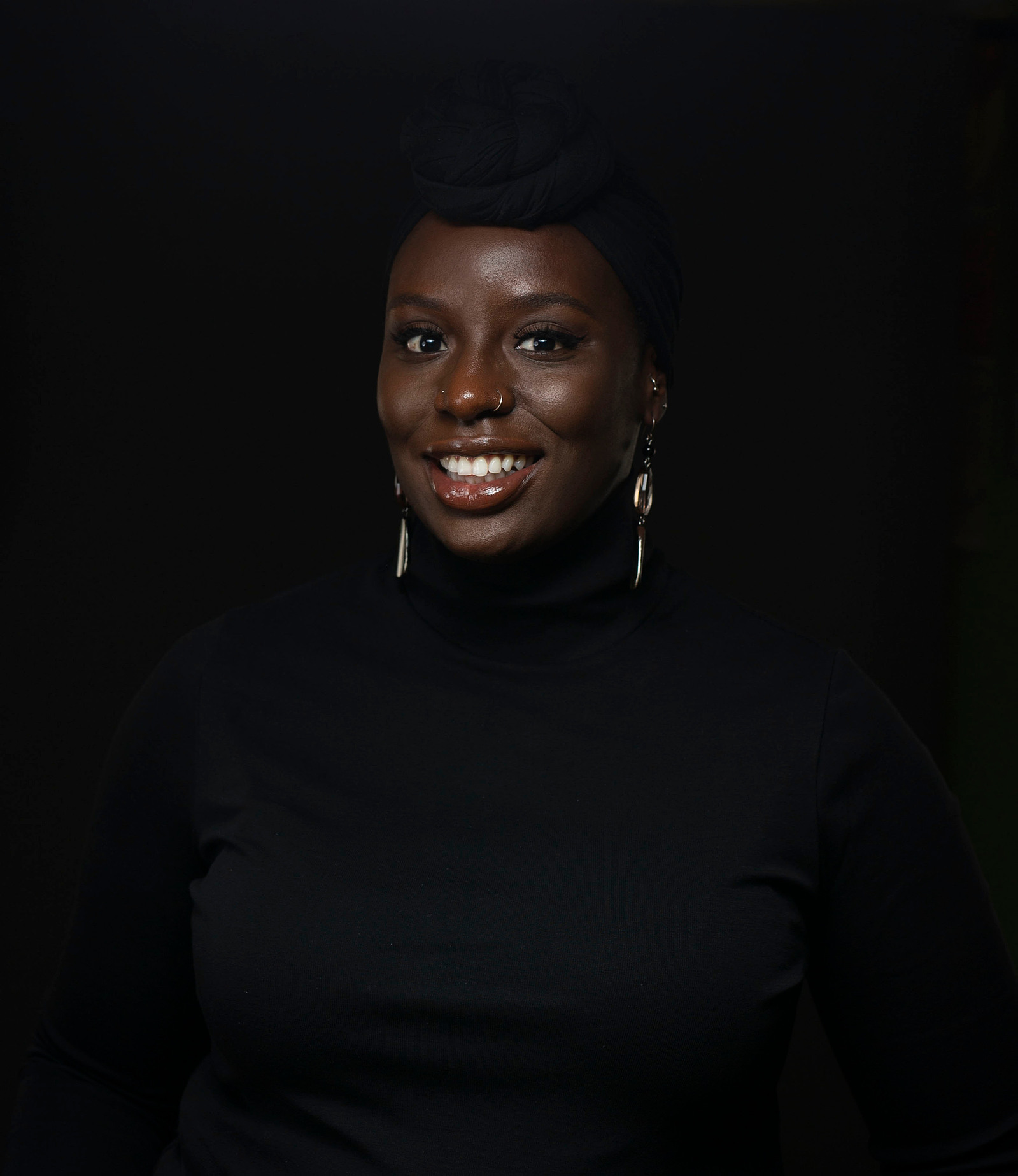 woman wearing a black head wrap and black turlte neck top
