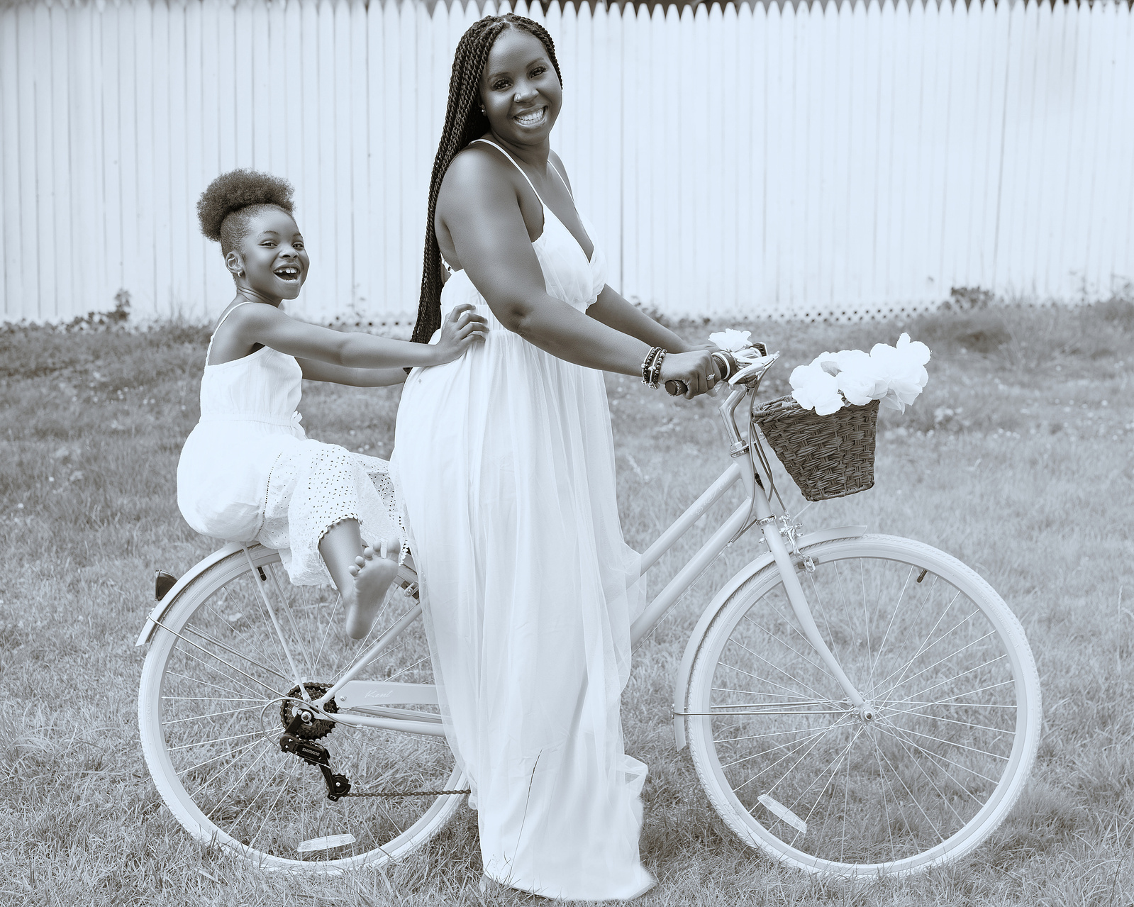 woman dressed in white with her daughter on a bicycle