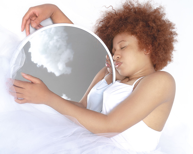 woman holding mirror while laying down