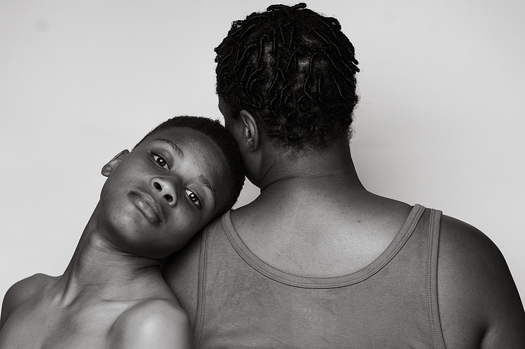 black woman with her teenage son, resting his head on her shoulder.
