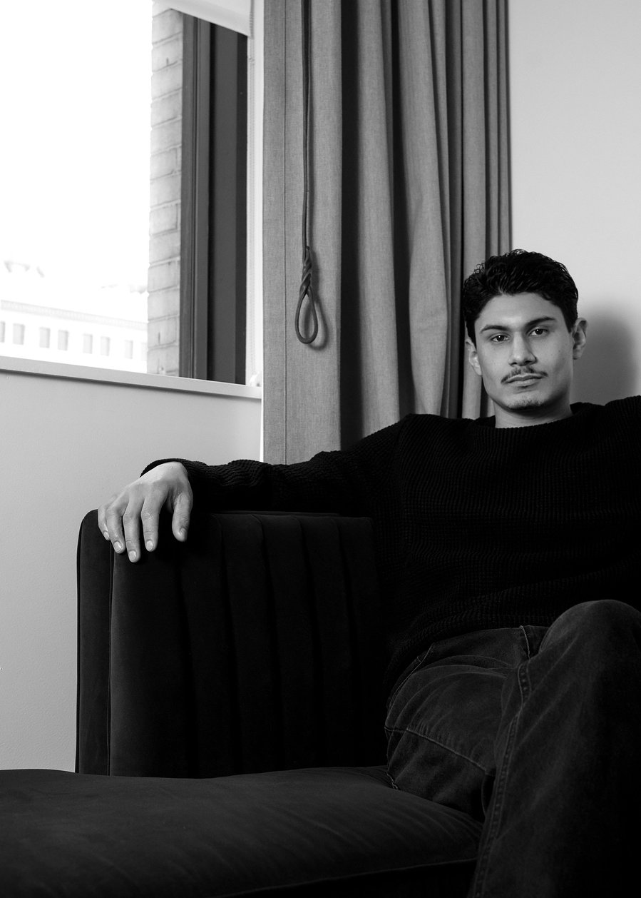 A male model wearing a black shirt and dark denim jeans