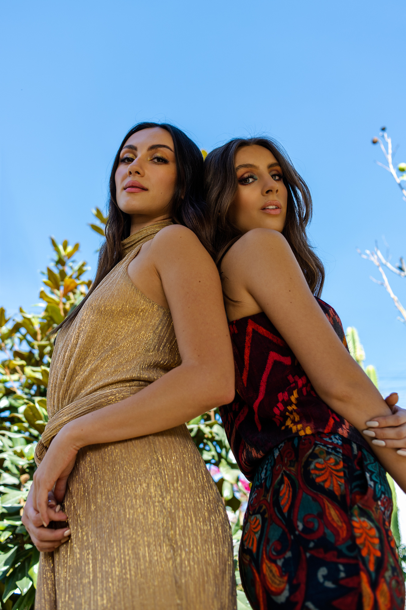 modelos en retrato editorial exterior con moda de fiesta y maquillaje profesional, en el jardín, posando de pie espalda con espalda, puebla, méxico