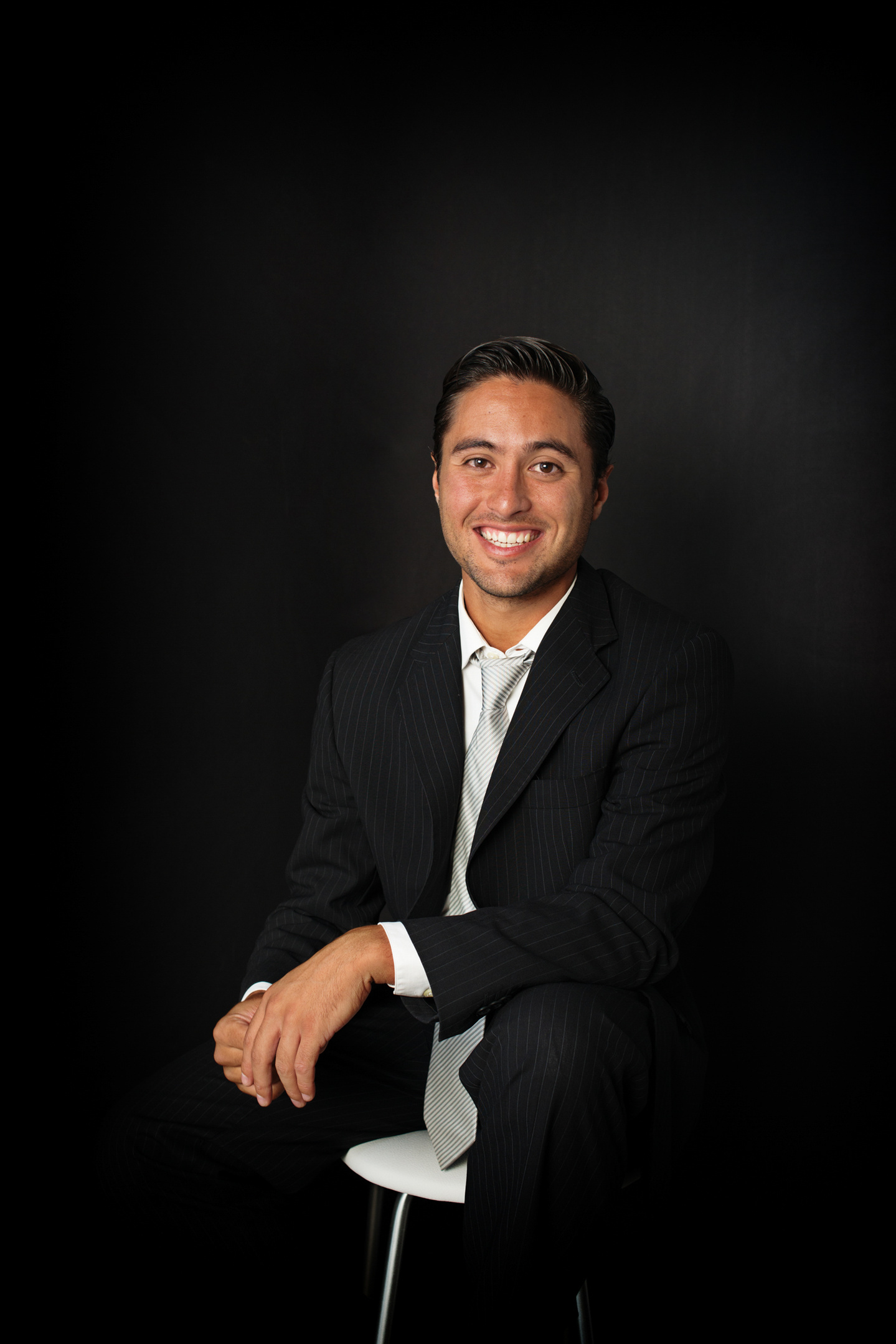 retrato corporativo headshot en estudio de hombre con atuendo profesional sentado en fondo oscuro