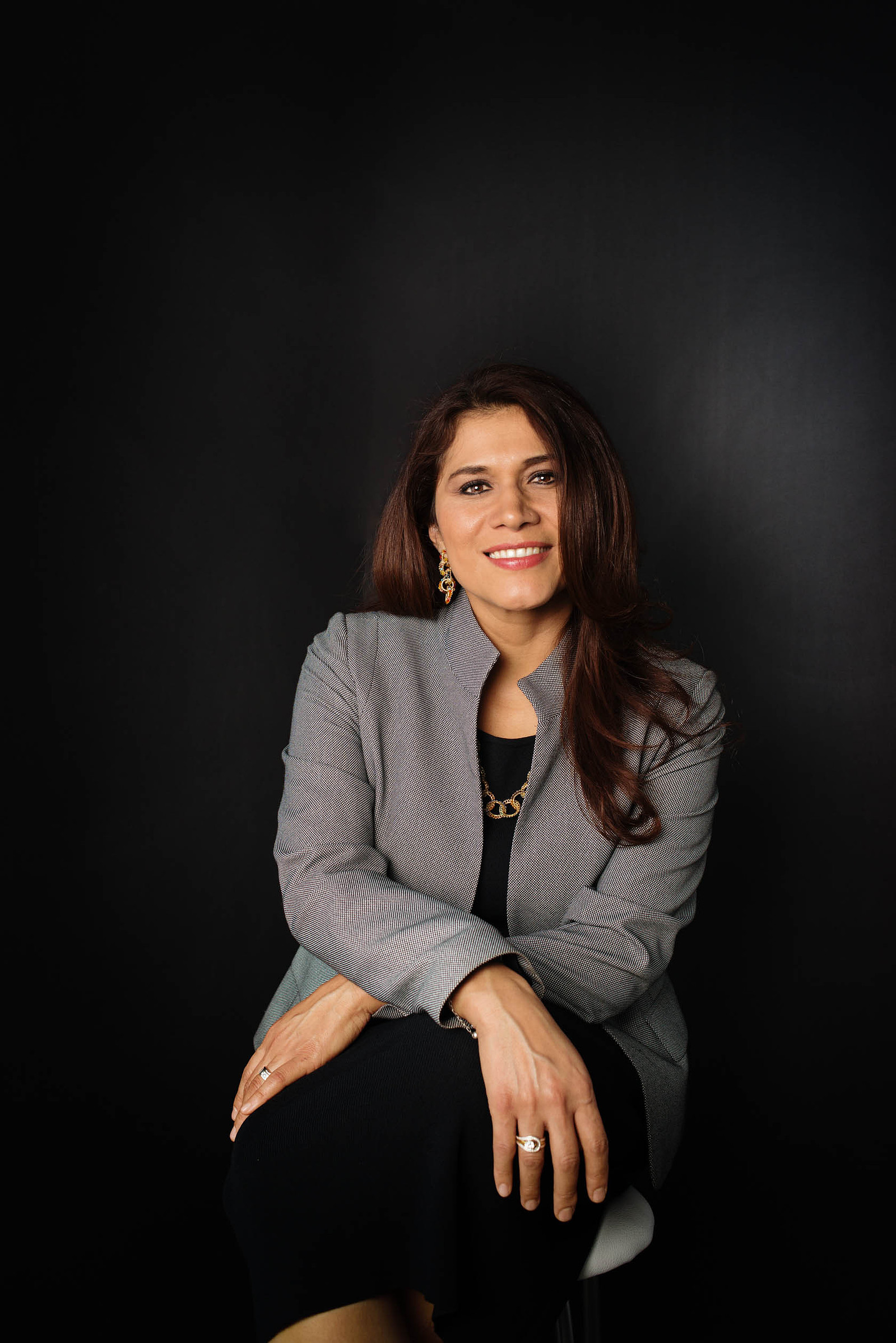 retrato corporativo headshot en estudio de mujer con atuendo profesional sentado en fondo oscuro