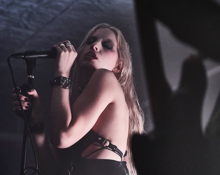 The musician Stella Rose singing into a microphone as she is performing at her record launch party, Fall 2021. Shot on Olympus EM1mkiii