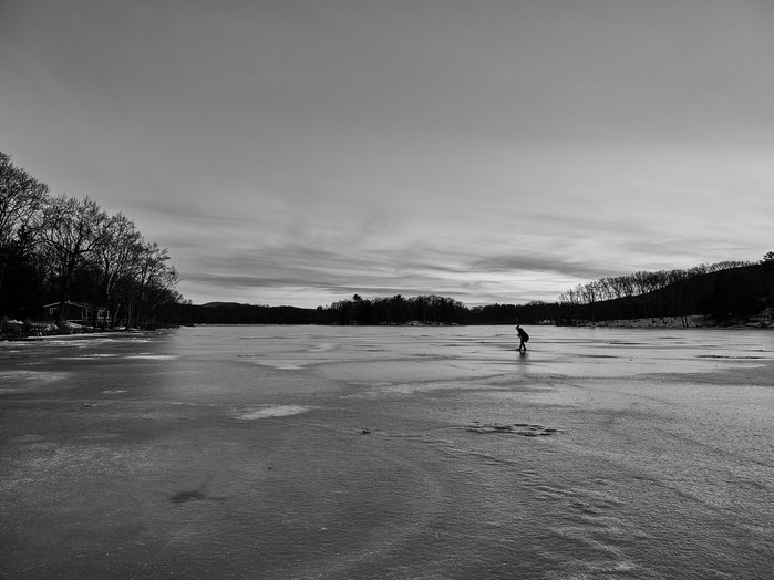 A frozen lake in winter, a woman standing on the lake in the distance.