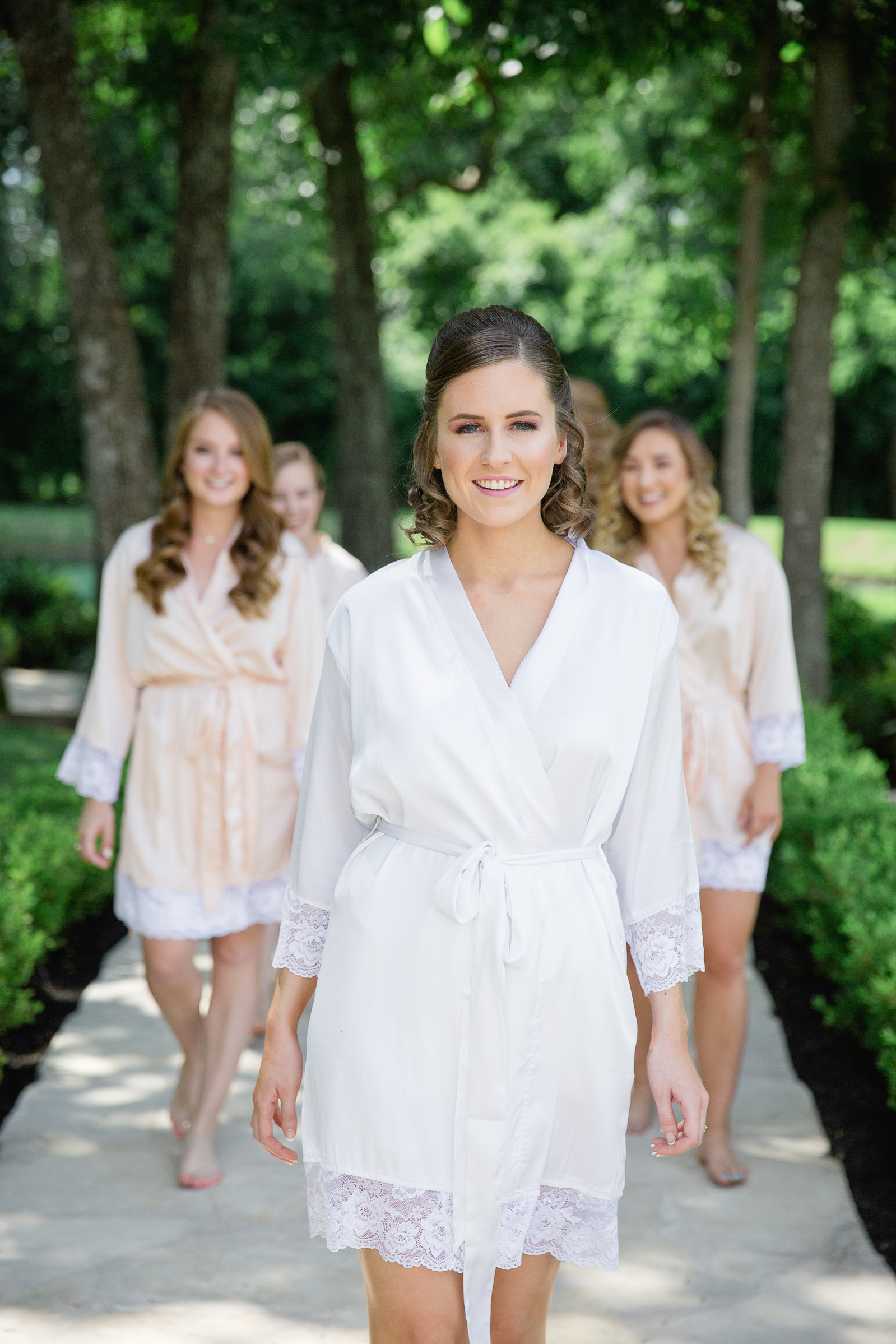 bride on white hobby walking happily with bridesmaids at the Springs venue in Katy TX