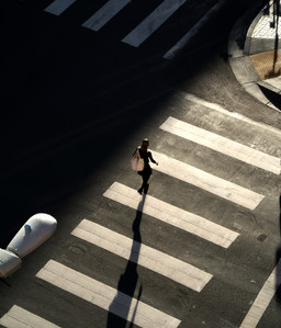 Abstract picture of a woman crossing the intersection with harsh lighting. 