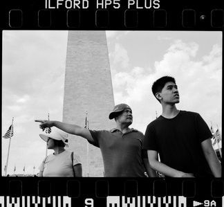 A family of three standing in front of the Washington monument. Captured on black and white film.